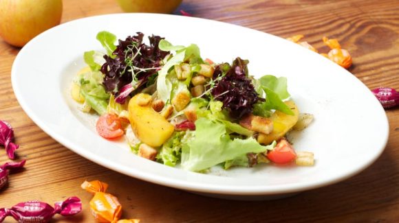 Starter colorful Lettuce Salad with glazed Apple Pieces, roasted Bread Croutons and Sea Buckthorn-Elder-Vinaigrette