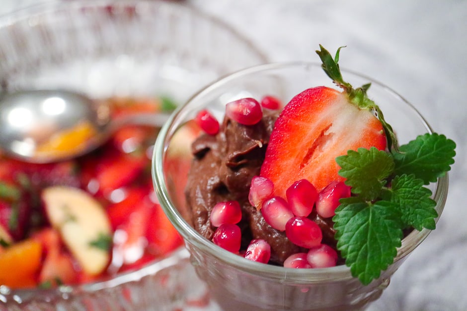 Vegan chocolate mousse decorated with mint, strawberry and pomegranate seeds