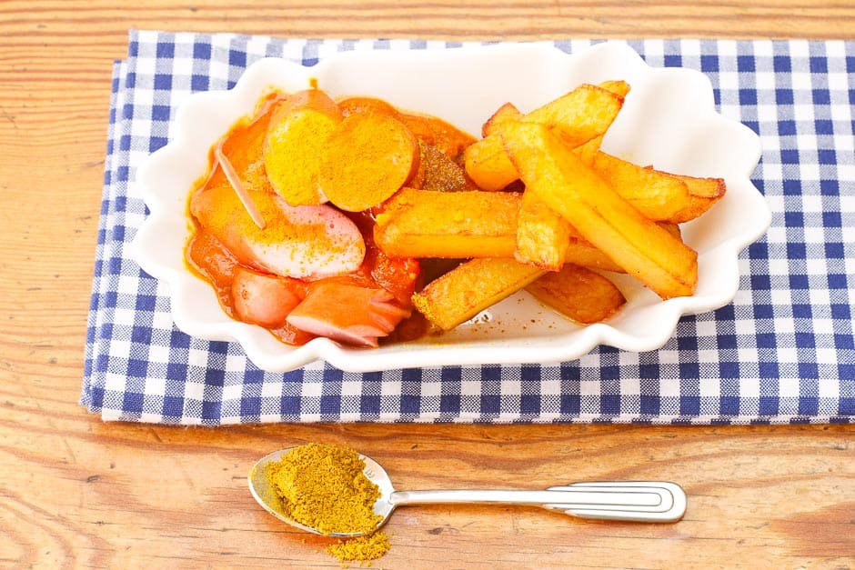 Currywurst cut open with currywurst sauce and french fries served