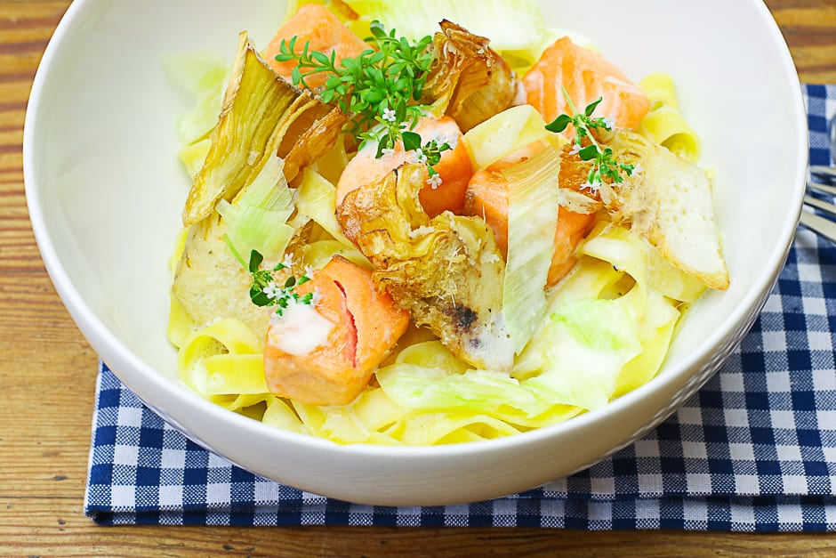 Salmon noodles with lemon sauce and artichokes served in a bowl.