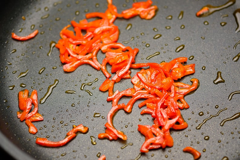 Stripes of peppers while frying in the pan, photographed from above Step picture.