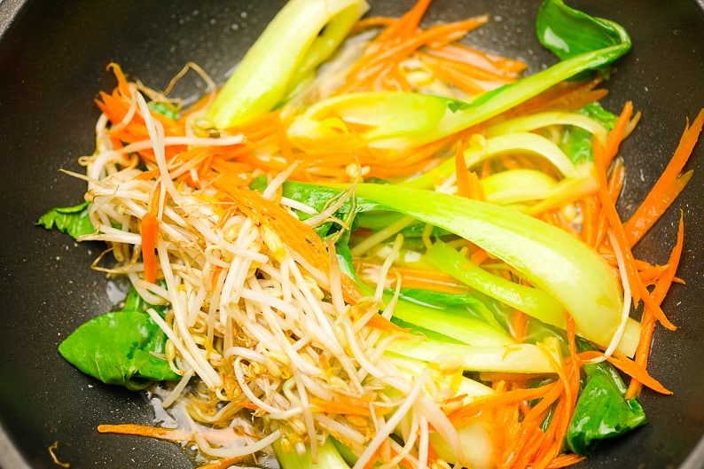 Vegetables steamed in the pan: carrot strips, pak choi, bean sprouts.