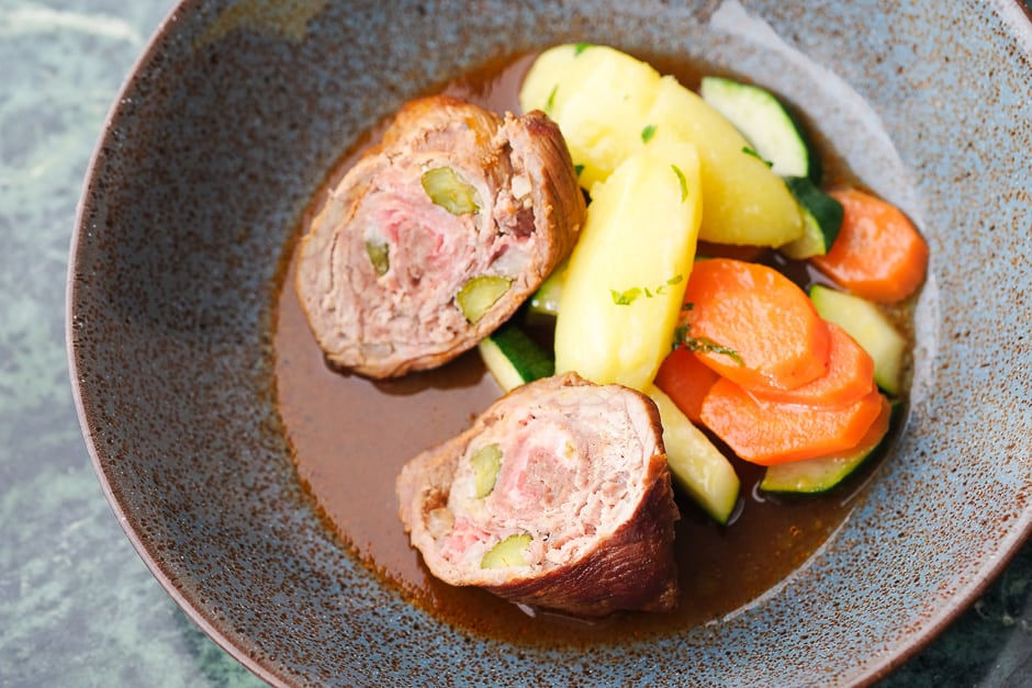 Beef roulade served with sauce and side dishes.
