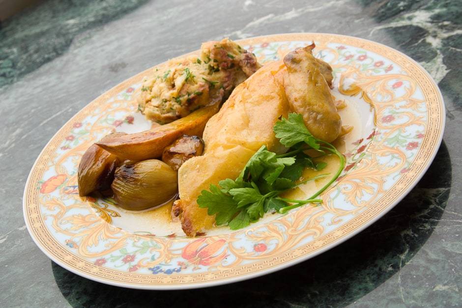 Roast chicken with crispy skin and side dishes served on a plate.