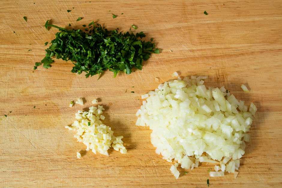 Finely dice onions and garlic, finely chop parsley. Prepare the first step in the meatloaf.