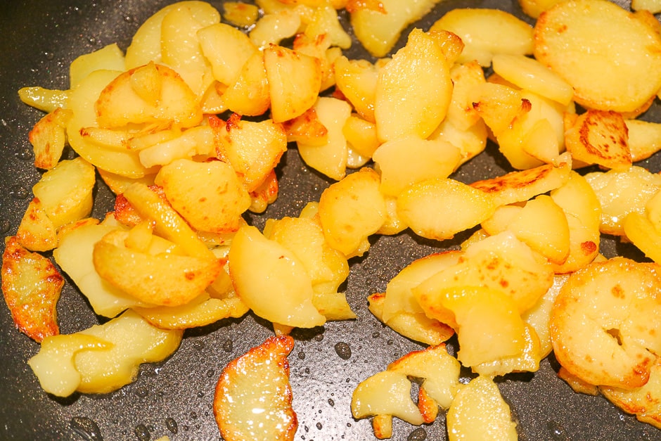Turn the fried potatoes in the pan.