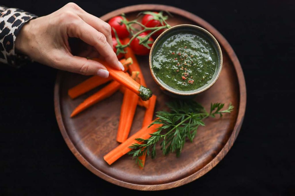 KArotte while dipping in carrot green pesto