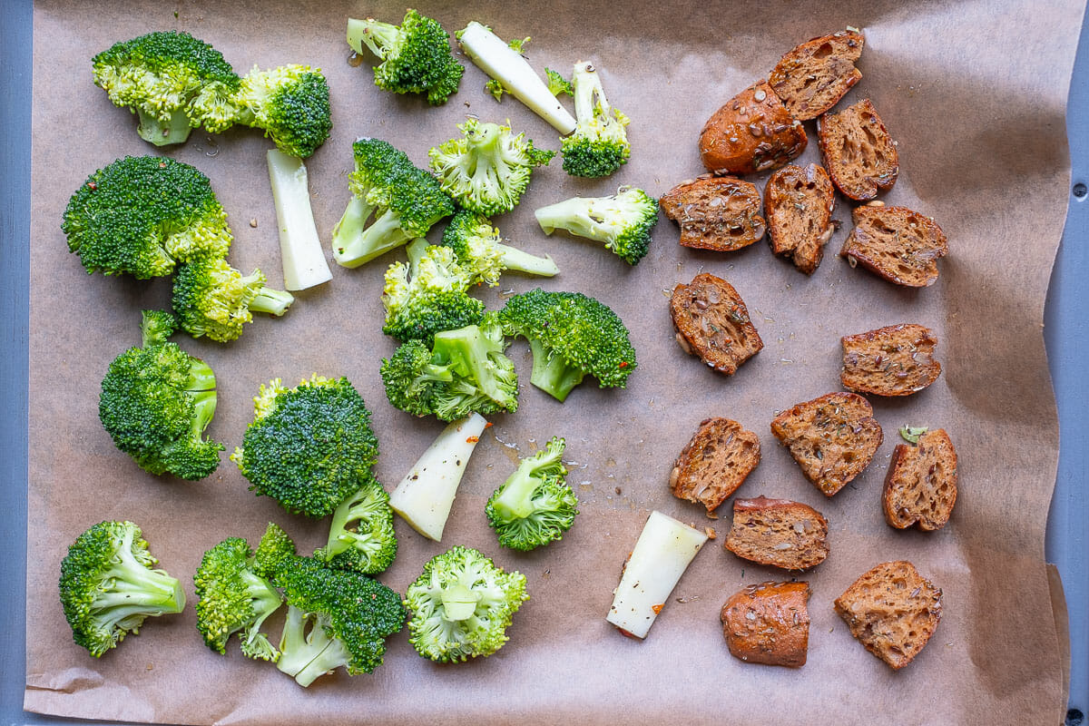 Raw broccoli and bread cubes on baking sheet