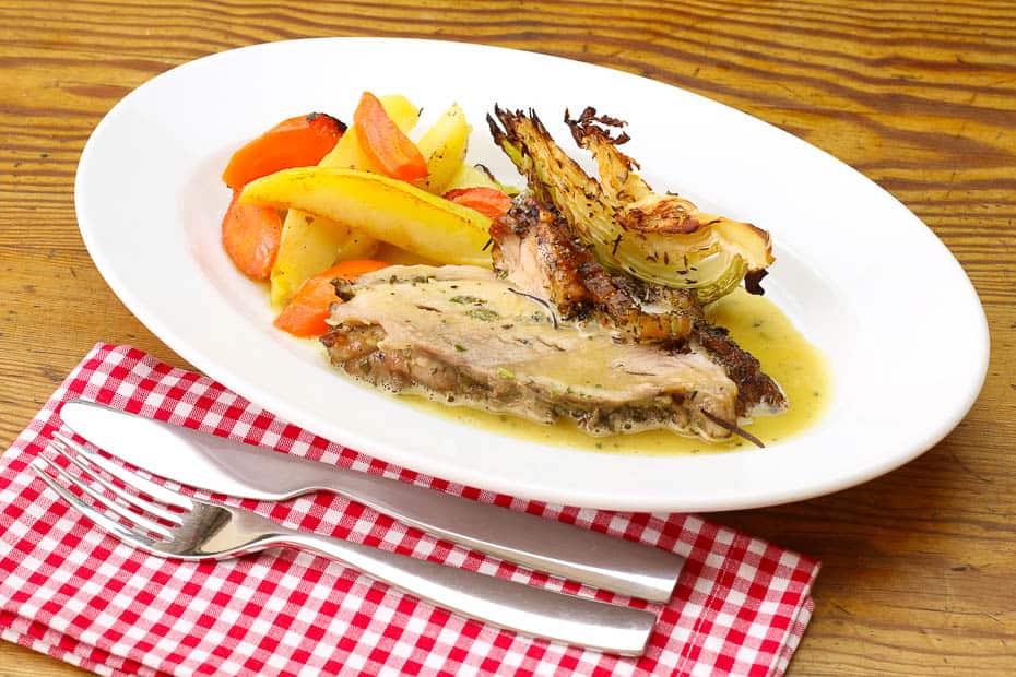 Roast pork served with vegetables and herb sauce