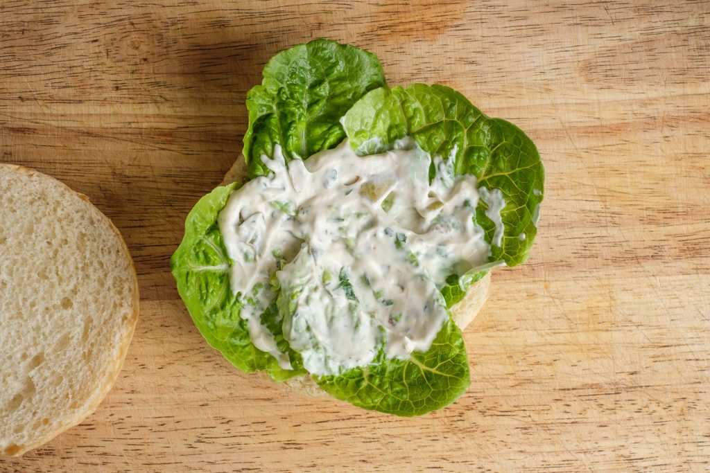 Top the fish sandwich with lettuce and remoulade.
