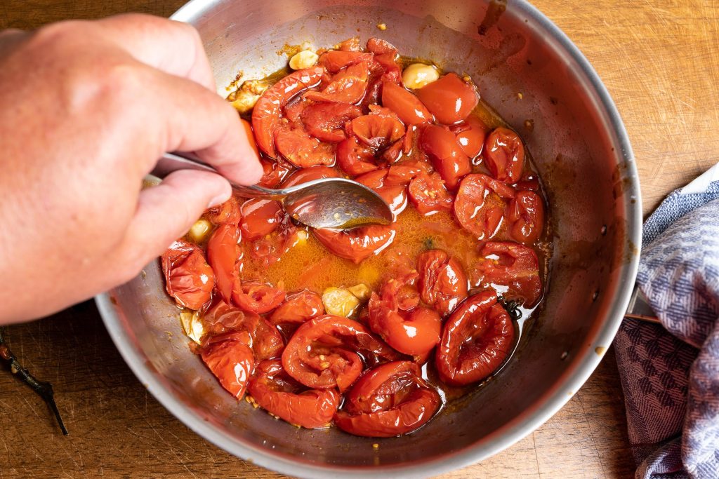 Crush the stewed tomatoes in the pot with a spoon