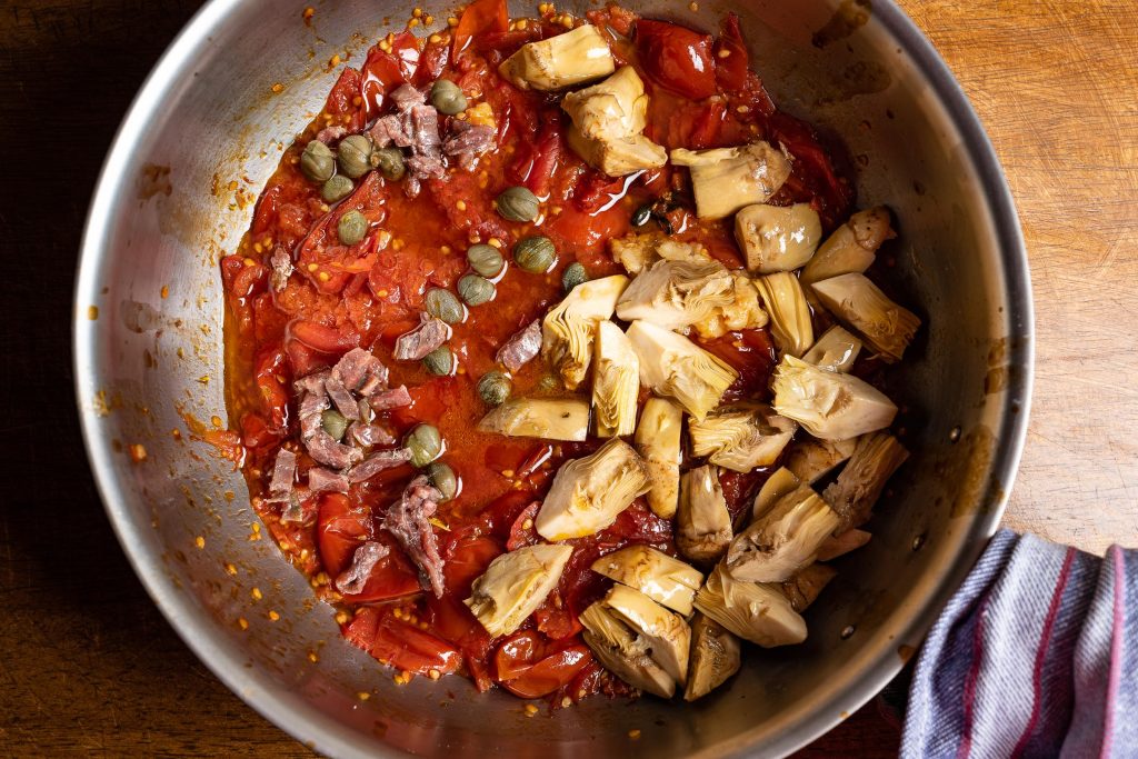 Braised tomatoes, capers, anchovies, artichokes in a pot